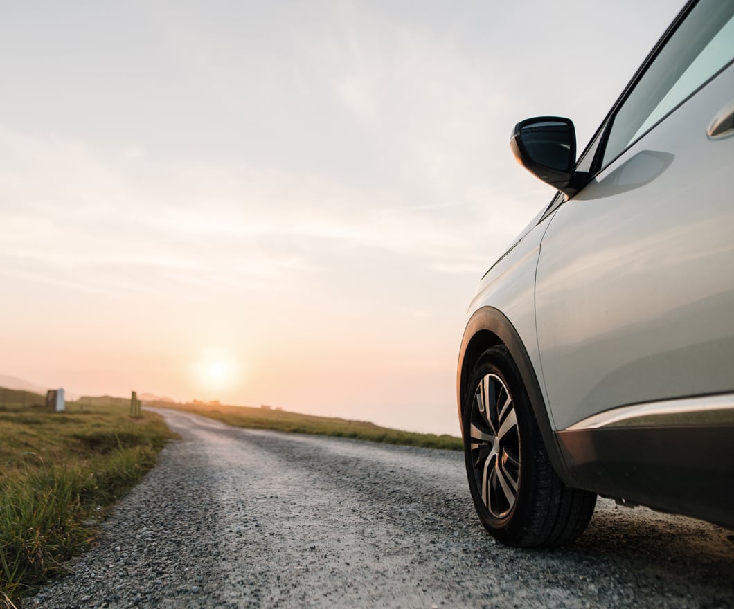 white-car-on-dirt-road-sunset-landscape